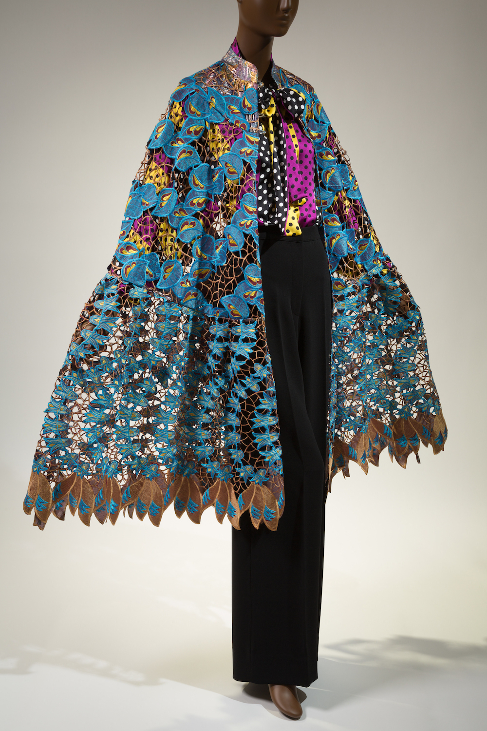 Ensemble; cape in blue & brown hand cut cotton & silk lace; multi-colored polka dot & stripe blouse in silk charmeuse; black crepe pants in wool & silk