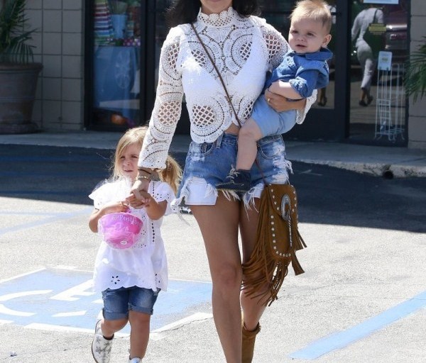 Get the Look: Kourtney Kardashian’s Woodland Hills Asilio White Walls Lace Crop Top, One Teaspoon Bandit Shorts, Saint Laurent Anita Fringe Bag, and Saint Laurent Wyatt Boots