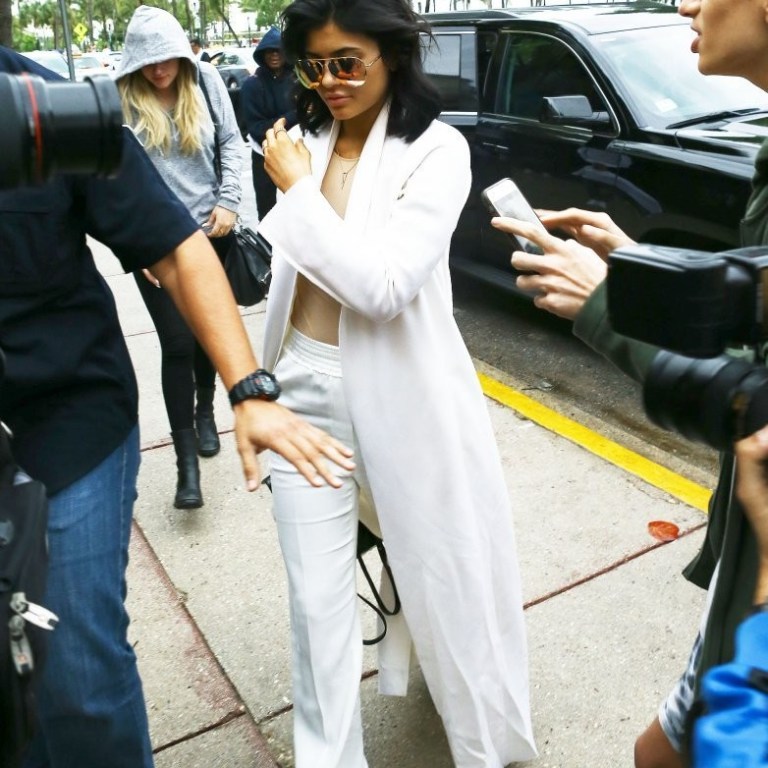 Get the Look: Kylie Jenner’s Miami Victoria Beckham Classic Victoria Gold Mirrored Sunglasses, The Row Nalaton Coat, Maison Martin Margiela Stretch Jersey Bodysuit, 3.1 Phillip Lim Straight Leg Pants, and Acne Studios Adrian Sneakers