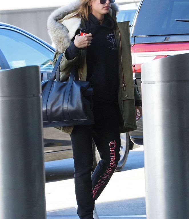 Splurge: Hailey Baldwin’s JFK Airport $4,590 Saint Laurent Green Hooded Parka, $550 Vetements Black Turned On By Danger Pants, and $435 Alexander McQueen Exaggerated Sole Sneakers