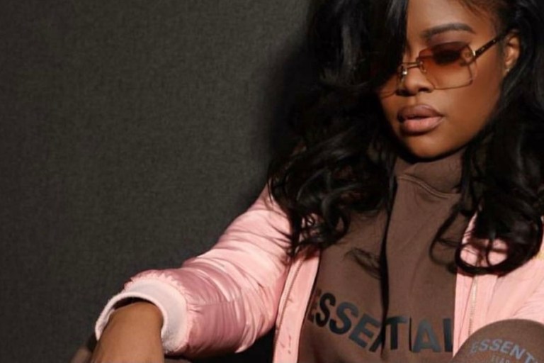 Karen Civil Rocks Brown Essentials by Fear of God Logo Hoodie and Sweatpants With Pink and Brown Louis Vuitton Clapton Backpack and Travis Scott x Air Jordan 1 Sneakers