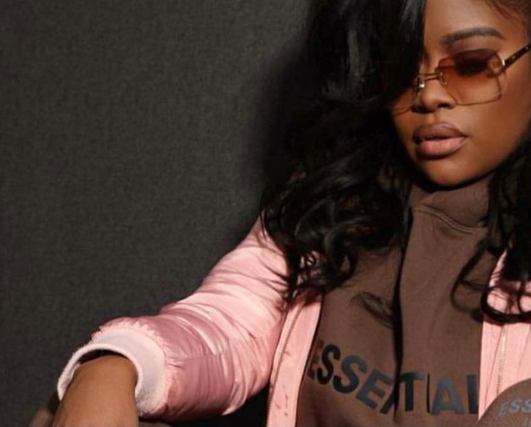 Karen Civil Rocks Brown Essentials by Fear of God Logo Hoodie and Sweatpants With Pink and Brown Louis Vuitton Clapton Backpack and Travis Scott x Air Jordan 1 Sneakers