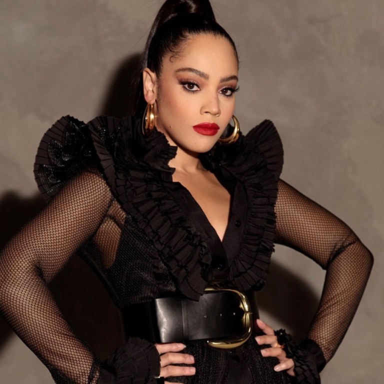 Bianca Lawson Posed for an Shoot Wearing a UNTTLD Black Ruffled Fishnet Mesh Dress With Berna Peci Gold Hoops and Nasty Gal Accessories