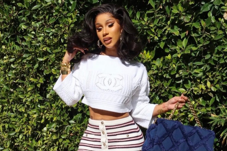Cardi B Is Spring-Ready in Chanel Cruise 2021 Look Including White Cable Knit Logo Sweater, Striped Knit Button Mini Skirt and Navy Cotton Canvas and Calfskin Flap Bag