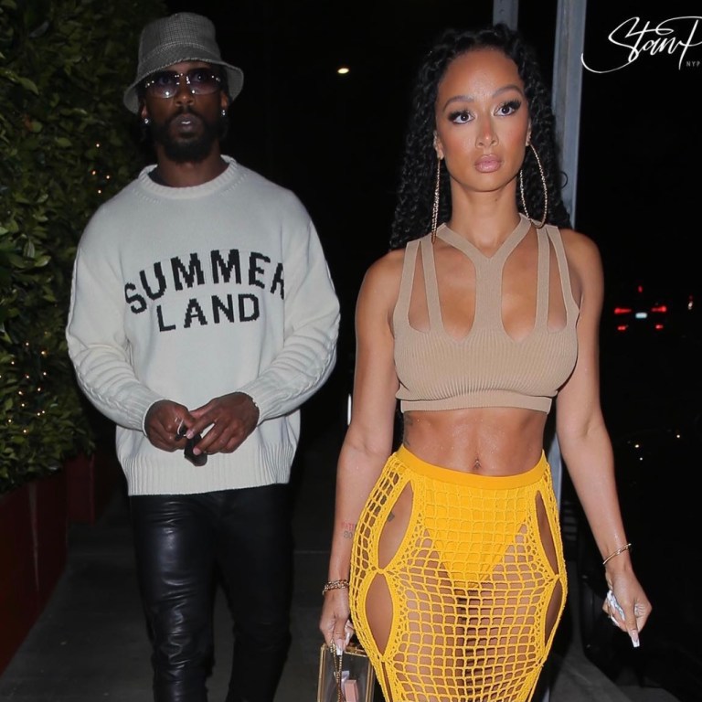 Draya Michele Spotted in Dion Lee Tan Knit Cutout Crop Top and Yellow Crochet Skirt During Outing With Tyrod Taylor in Nahmias Sweater, 1017 ALYX 9SM Black Leather Pants, Celine Plaid Bucket Hat and Rick Owens Sneakers