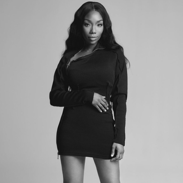 Brandy Stuns in Black and White Photoshoot Wearing Lionne Clothing Black Long Sleeve Zip-Up Mini Dress and Femme LA Black Lace-Up Sandals