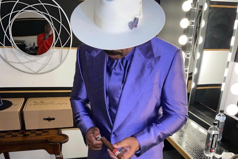 Steve Harvey Hosts Verzuz Between Earth, Wind & Fire and the Isley Brothers Wearing Dolce and Gabbana Custom Purple Satin Suit and Meshika White Hat