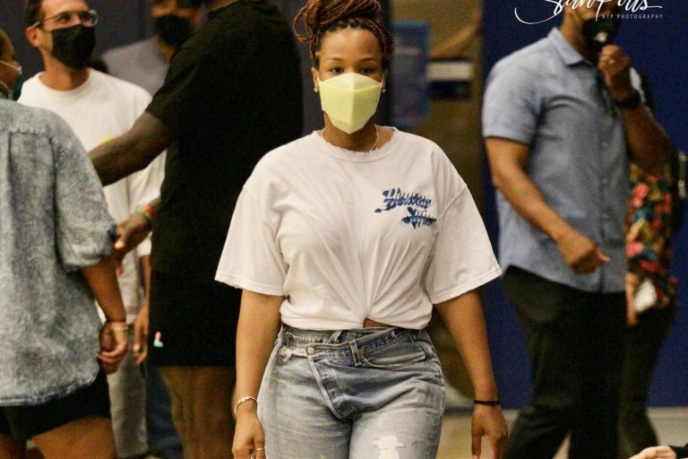 You Ask, We Answer! Savannah James Attends Bronny’s Game Wearing Boys Lie White Tee, Agolde Crossover Jeans, Bottega Veneta Green Chain Belt Bag and Aleali May x Air Jordan 1 Zoom Comfort Sneakers