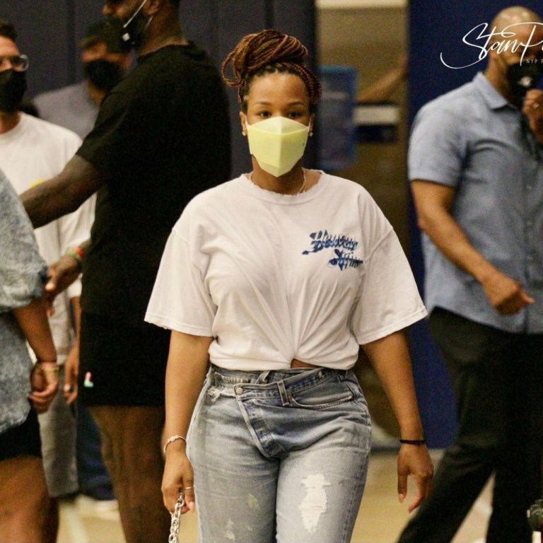 You Ask, We Answer! Savannah James Attends Bronny’s Game Wearing Boys Lie White Tee, Agolde Crossover Jeans, Bottega Veneta Green Chain Belt Bag and Aleali May x Air Jordan 1 Zoom Comfort Sneakers