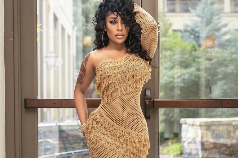 K. Michelle Stuns in Tularosa Tan One Shoulder Fringe Crochet Dress and Bottega Veneta Shearling Mules