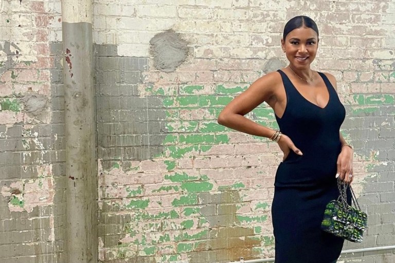 Eniko Hart Strikes a Pose While Slaying in a ALEXIS Black V-Neck Dress, Chanel Bag, and Off-White Black Bow Mules