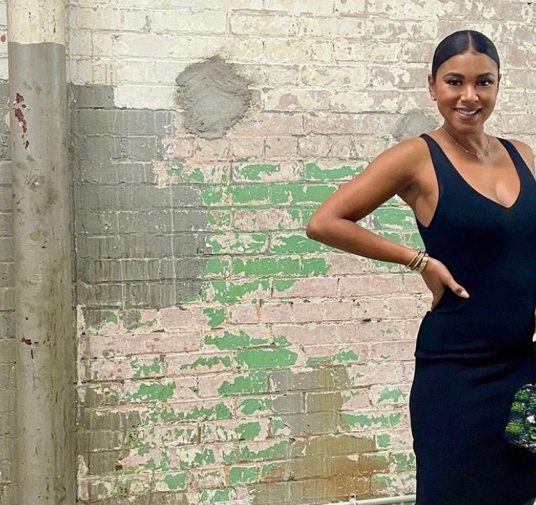 Eniko Hart Strikes a Pose While Slaying in a ALEXIS Black V-Neck Dress, Chanel Bag, and Off-White Black Bow Mules