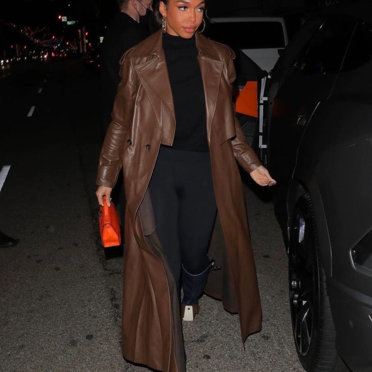 Lori Harvey Grabs Dinner in Beverly Hills Wearing Bottega Veneta Brown Leather Trench Coat, Wolford Black Top and Leggings and Louis Vuitton Colorblock Knee-High Wedge Boots