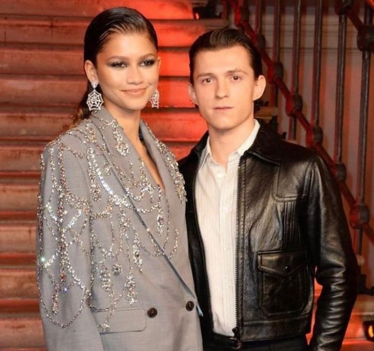 Zendaya and Tom Holland Are ‘Couple Goals’ at the London Premiere of ’Spider-Man: No Way Home”: Zendaya Wears Alexander McQueen Spring 2022 Crystal-Embroidered Grey Blazer Jacket and Thigh-High Boots With Tom Holland in Celine