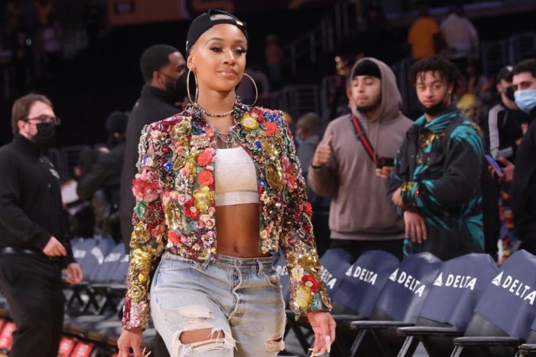 Wardrobe Inquiry: Saweetie Attends Lakers vs. Timberwolves Game in LA Wearing Dolce and Gabbana Embellished Jacket and Pink Heels Paired with White Crop Top, Distressed Jeans and Goodie Black Hat