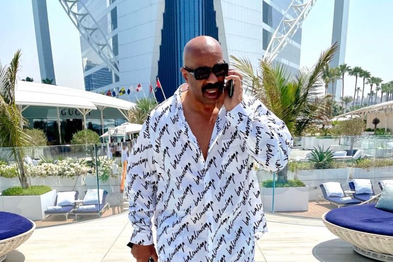 Steve Harvey Steps out in Dubai In a Balenciaga Black and White Logo Scribble Shirt, Matching Pajama Pants, and a Dior x Rimowa Cigar Holder + See Him Mention BeautyLifeFun on Earn Your Leisure!