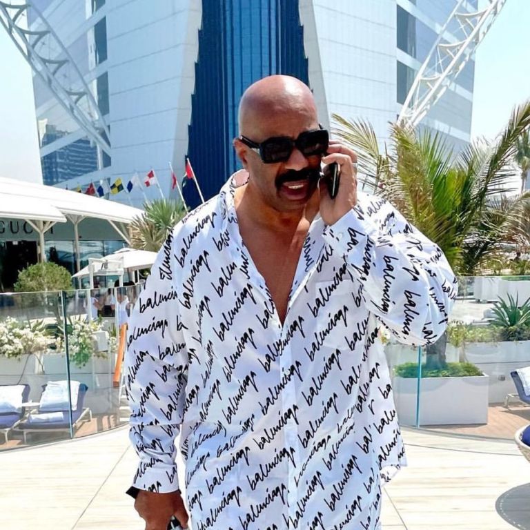 Steve Harvey Steps out in Dubai In a Balenciaga Black and White Logo Scribble Shirt, Matching Pajama Pants, and a Dior x Rimowa Cigar Holder + See Him Mention BeautyLifeFun on Earn Your Leisure!