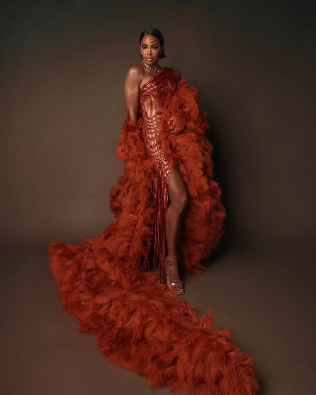 Kelly Rowland Posed In An Orange Chocolate Valdrin Sahiti Gown With Flor De Maria Sandals 3