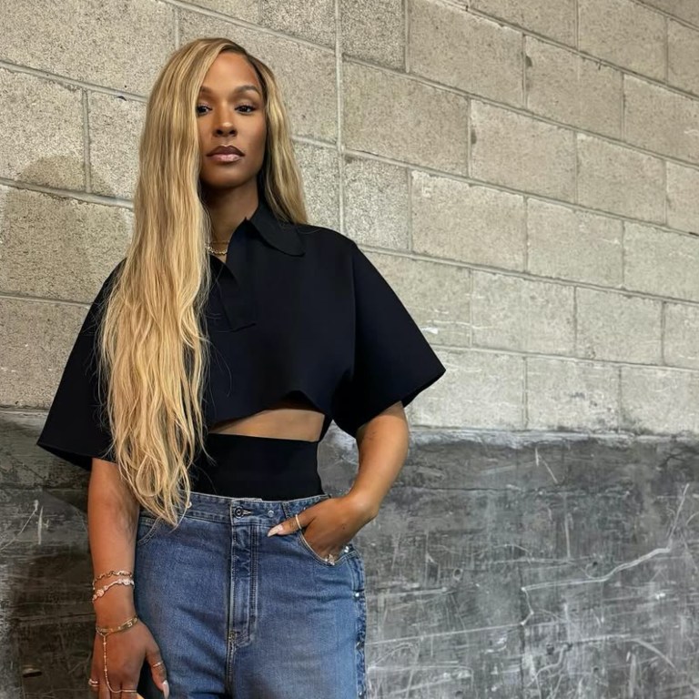 Savannah James Attends Basketball Game Wearing an Alaia Cropped Black Polo Shirt, Snap Denim Jeans, Louis Vuitton Green Speedy, and Bottega Veneta Mules