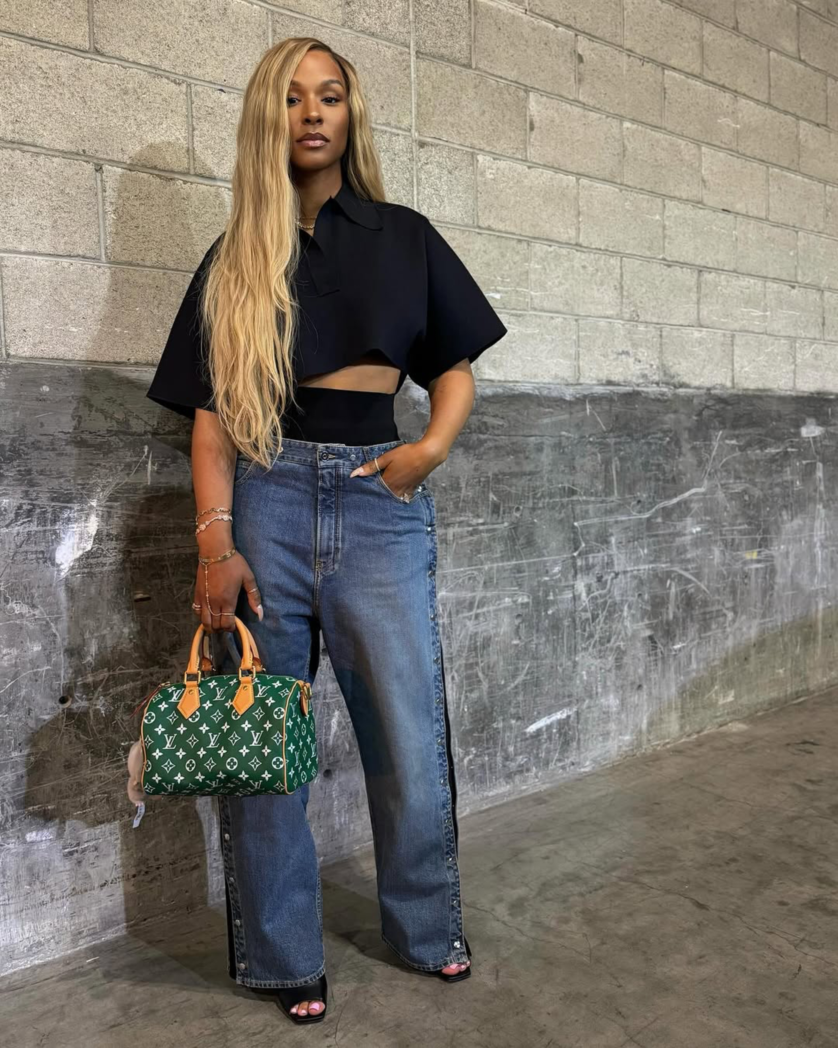 Savannah James Attends Basketball Game Wearing An Alaia Cropped Black Polo Shirt Snap Denim Jeans Louis Vuitton Green Speedy And Bottega Veneta Mules